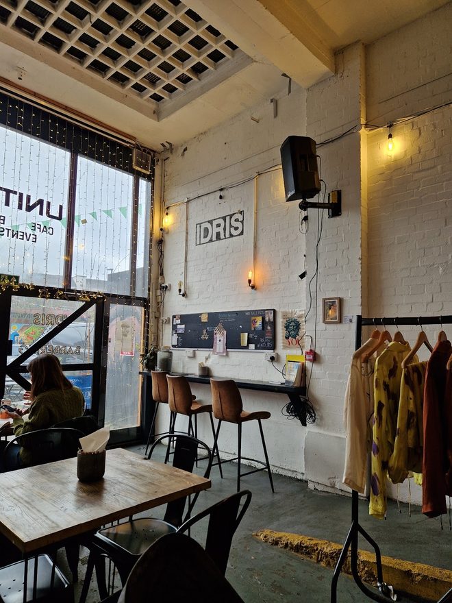 A grilled panini beside a takeaway coffee on a weathered pallet table