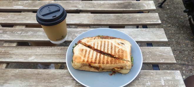 A shared table of sandwiches, crisps and coffee